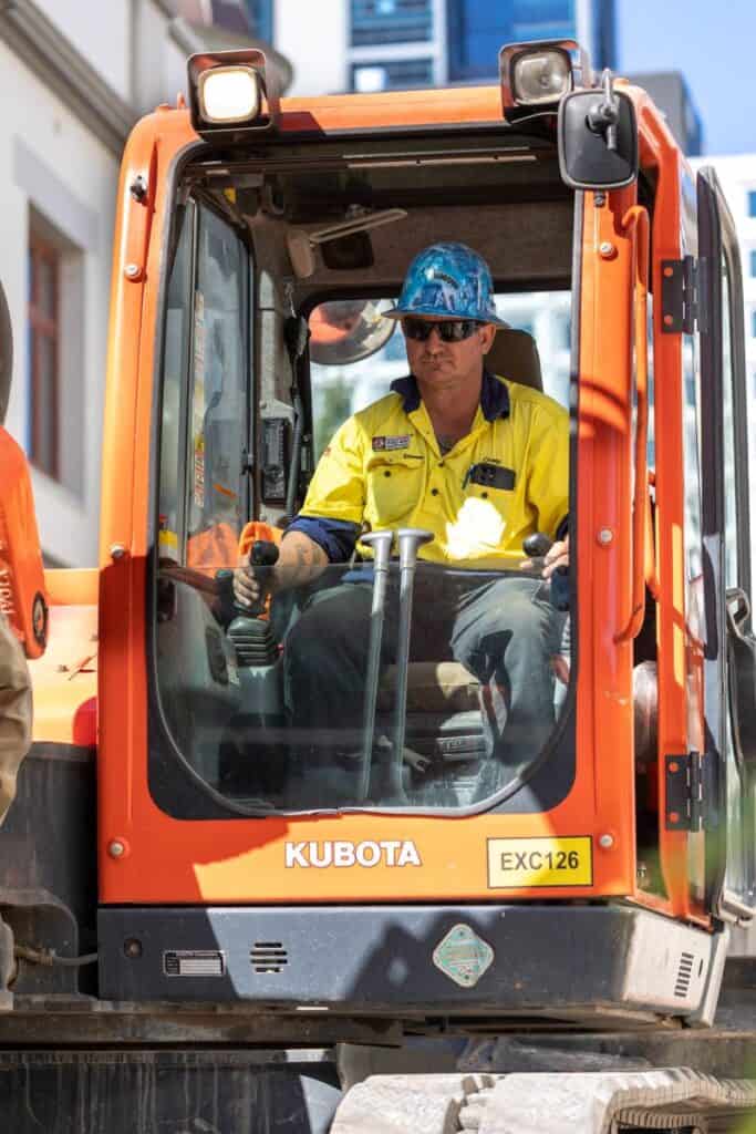 Kubota mini excavator operator at construction site, rentable mini equipment.